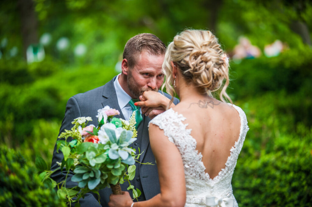 groom kissing bride's hand during first look